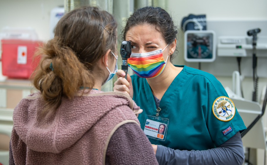 student Kate Slodowy wearing rainbow mask giving a patient assessment