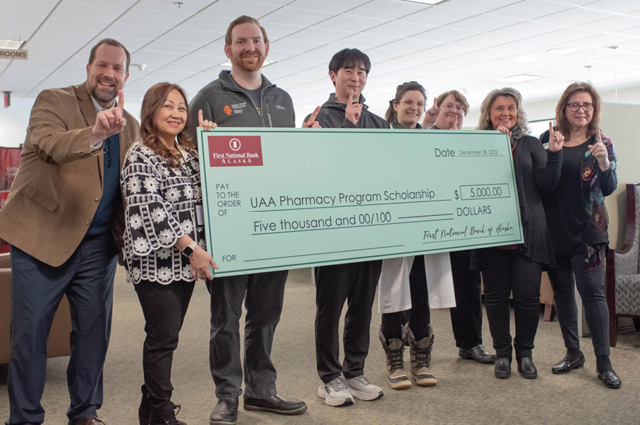 A formal check presented on behalf of Bernie's pharmacy for UAA Pharmacy Program Scholarship by smiling staff members
