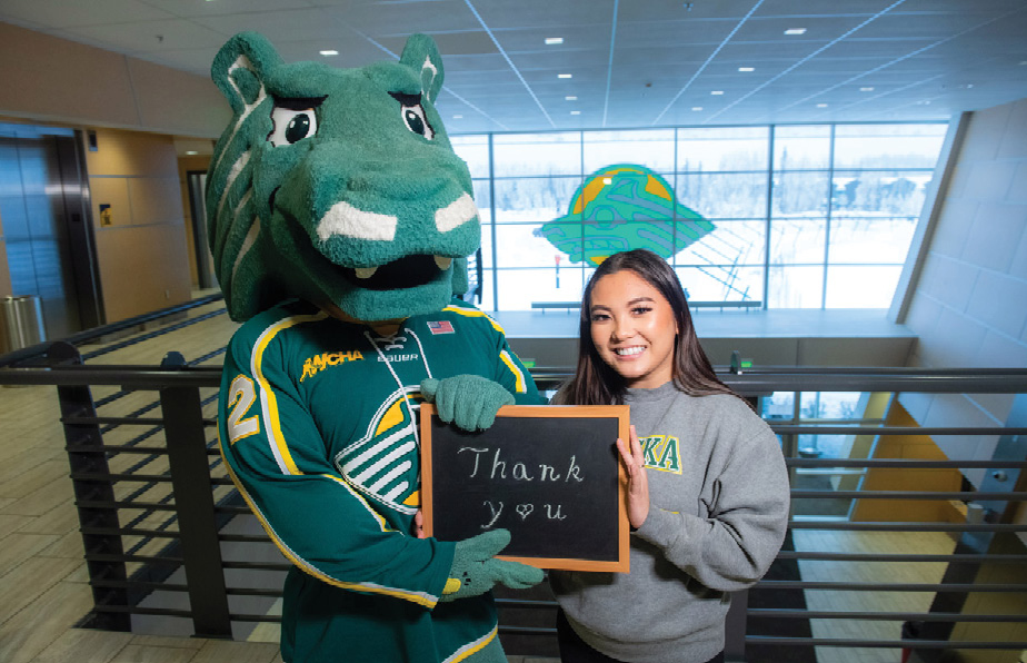 UAA Seawolves mascot and smiling student hold up a 'Thank you' sign in regards to over $324,000 raised on Giving Day 2023.