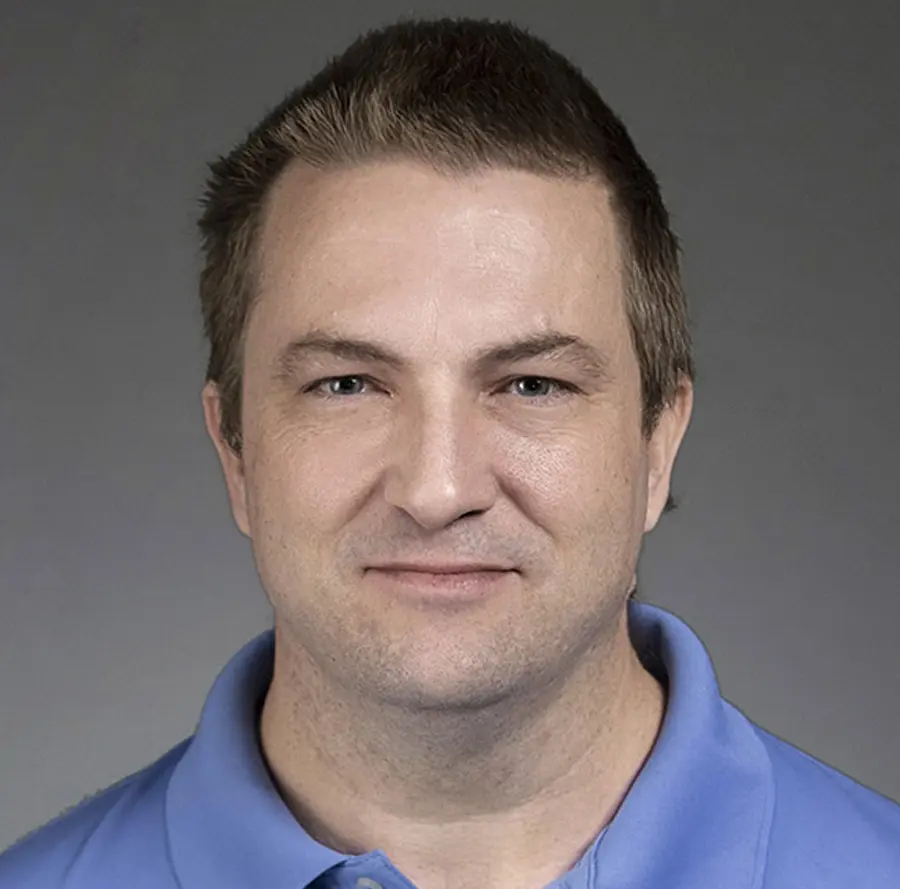 Portrait headshot close-up photo view of Jeremy Maxie grinning in a dark sky blue polo top