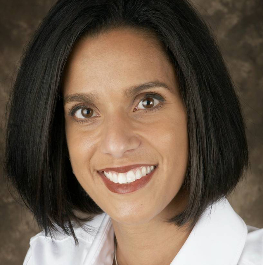 Portrait orientation close-up headshot photograph of Jennifer Schrage smiling in a white button-up dress shirt