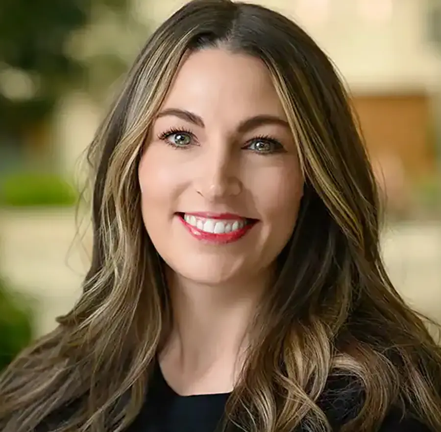 Headshot photograph of Desi Robb smiling in a black blouse top with red lipstick equipped