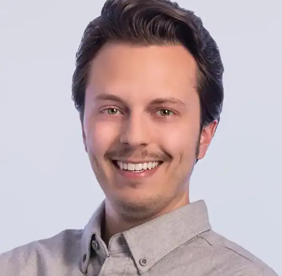 Headshot photograph of Jesse Wight-Crask smiling in a gray button-up dress shirt