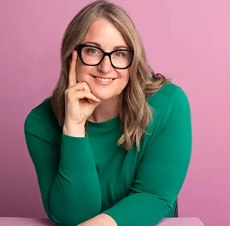Headshot photograph of Tasha Pineda smiling in a green sweatshirt blouse top with black presrciption eyeglasses