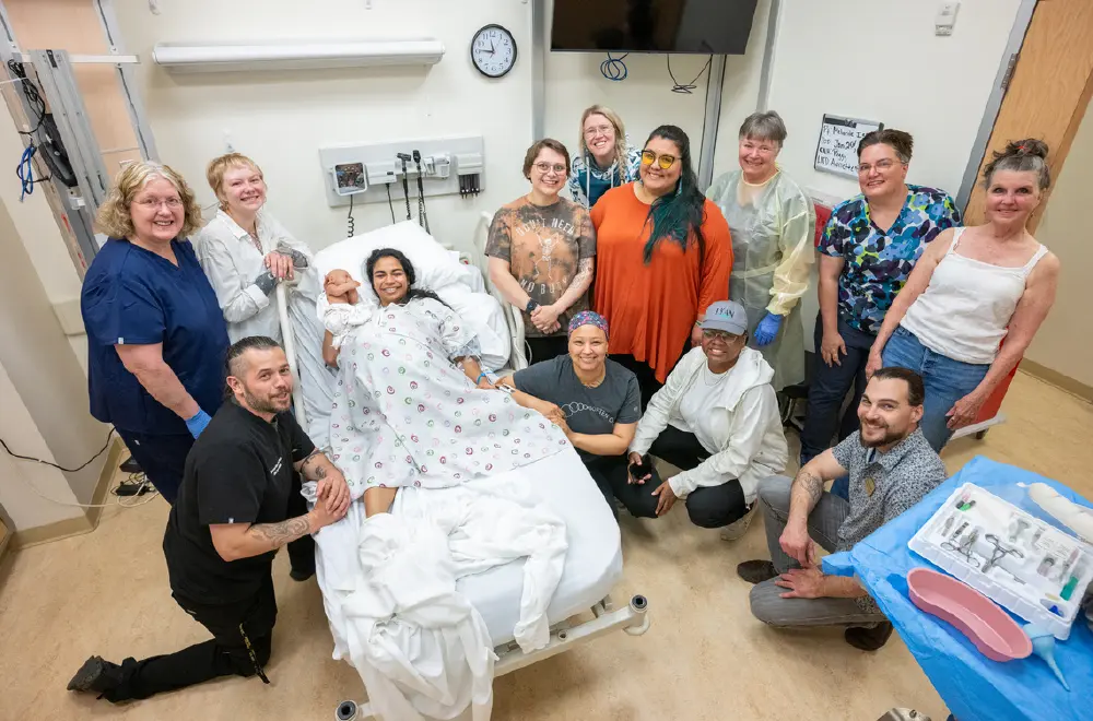 Simulation participants gather to celebrate a successful (simulated) birth as UAA College of Health Simulation Center uses a wearable Avbirth Childbirth Simulation Device for the first time to help train students in the Full Embrace Doula Program.