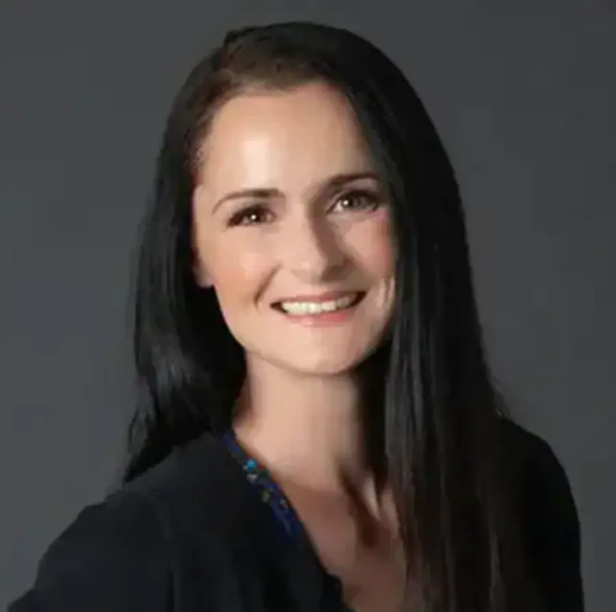 Headshot photograph of Courtney Maillet smiling in a black business blazer suit