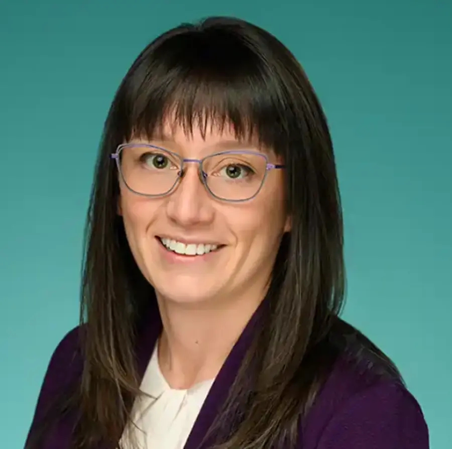 Headshot photograph of Csesalie Bates smiling in a violet business blazer suit