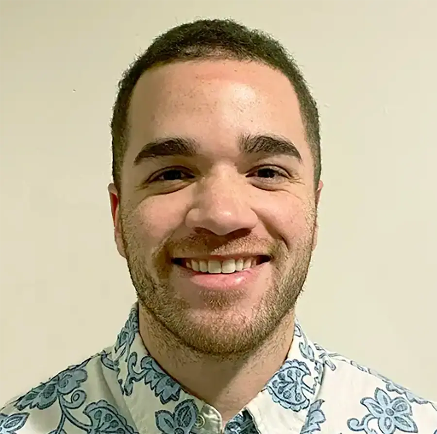 Headshot photograph of Eric Jones smiling in a floral pattern button-up dress shirt
