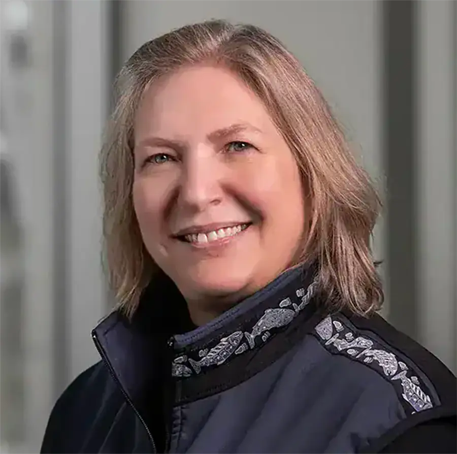 Headshot photograph of Gwen Welch smiling in a navy blue jacket