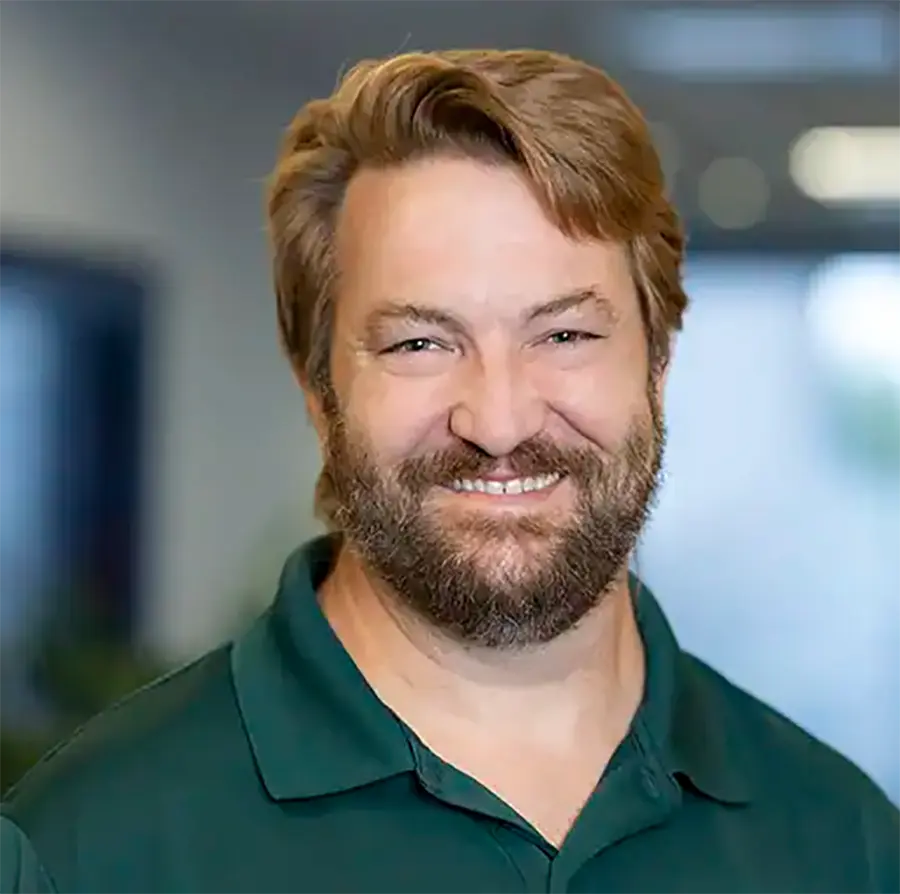 Headshot photograph of Jeremy Maxie smiling in a green polo top shirt