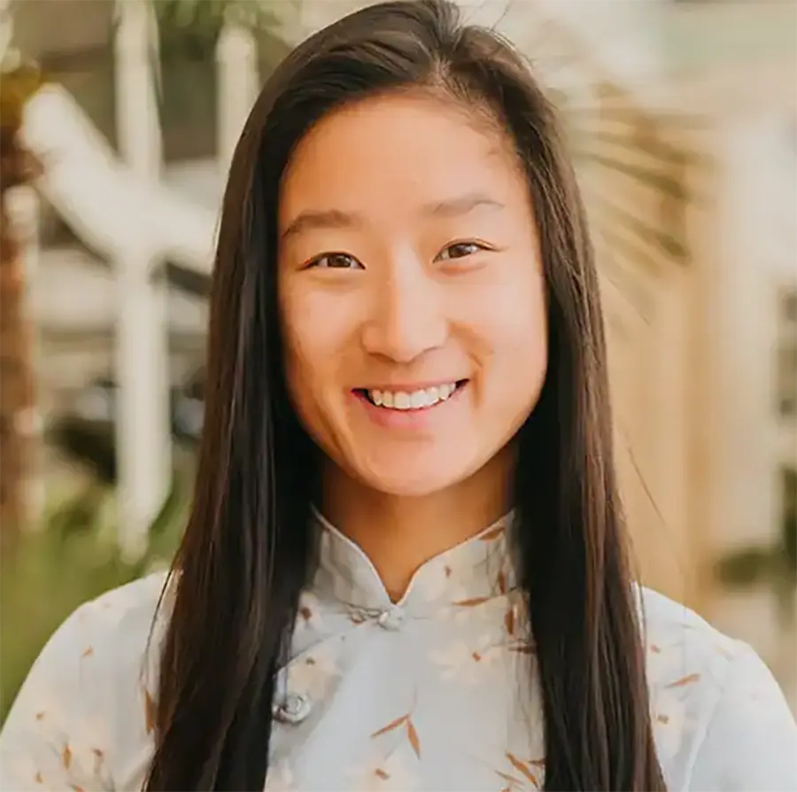 Headshot photograph of Joy Sumner smiling in a floral pattern blouse top